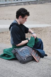 Kiefer High School senior Logan Holt makes room in his bag for some of the books her purchased while taking a break on the seashore side of Anglesey, Wales.