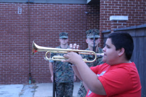 Sapulpa High School Trumpeter Nathaniel Adamson plays Taps alongside the Sapulpa High School Marine Corps JROTC rifle team members (left to right) Cadet 2nd Lieutenant Perry Pry and Cadet Sargent Ford Jacob Ford.