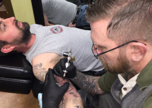 Brandon Mull of Mission Street Tattoo works on one of his customers.