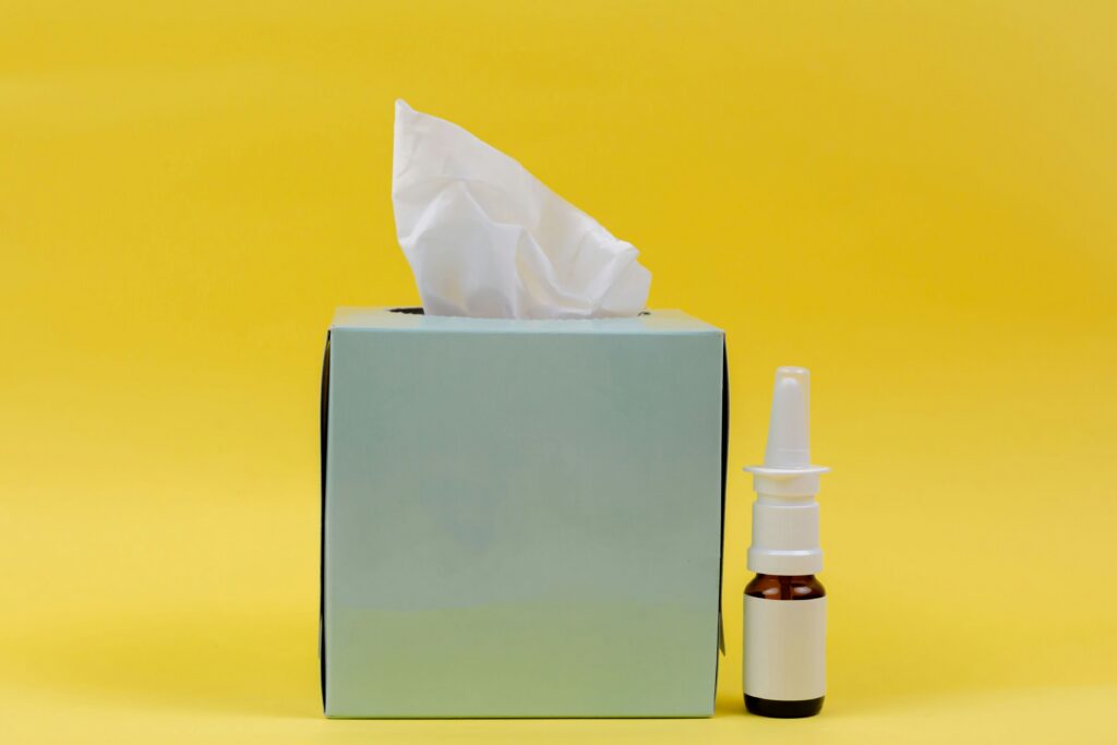 Nasal spray and paper napkins in a blue box on a yellow background. Medicine. Disease. Cold. Coronavirus. Covid- 19. Nasal spray,allergy. nasal secretion